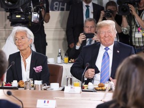 U.S. President Donald Trump, right, takes his seat after arriving late for the G7 and Gender Equality Advisory Council Breakfast, as IMF Managing Director Christine Lagarde looks on, left, at the G7 leaders summit in La Malbaie, Que., on Saturday, June 9, 2018.