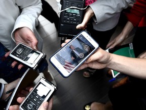 Canadian journalists watch a live feed as U.S. President Donald Trump speaks to members of the White House press pool before departing from the G7 leaders summit in La Malbaie, Que., on Saturday, June 9, 2018.