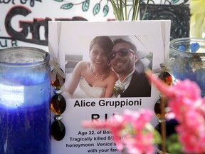 FILE - In this Aug. 5, 2013 file photo, a card showing a photo of Italian newlyweds Alice Gruppioni, left, and her husband Christian Casadei, is placed on a makeshift memorial for Gruppioni along Ocean Front Walk at Venice Beach in Los Angeles. An attorney for the family of Gruppioni, who was killed when a driver barreled down the popular Venice Beach Boardwalk, says Los Angeles has approved a $12 million settlement in the case. The Los Angeles city council approved the settlement Tuesday, June 5, 2018, with the family.