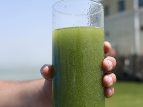 FILE - In this Aug. 3, 2014 file photo, a sample glass of Lake Erie water is photographed near the City of Toledo water intake crib on Lake Erie, off the shore of Curtice, Ohio. Researchers and officials across the country say increasingly frequent toxic algae blooms are another bi-product of global warming. They point to looming questions about their effects on human health.