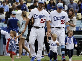 As part of a Father's Day celebration, Los Angeles Dodgers starting pitcher Clayton Kershaw (22) and relief pitcher Tom Koehler walk onto the field with their children before a baseball game against the San Francisco Giants in Los Angeles, Sunday, June 17, 2018.