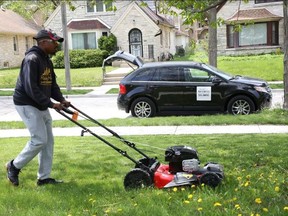 Rodney Smith, 28, of Alabama mows a lawn in Milwaukee. He's mowing lawns across the country for free to help people in need.