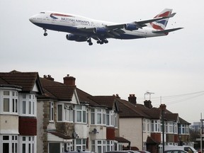FILE - In this Tuesday, Oct. 25, 2016 file photo, a plane flies over nearby houses as it approaches for landing at Heathrow Airport in London. The British Cabinet on Tuesday June 5, 2018, is expected to approve the construction of a third runway at Heathrow Airport, and to put the long-running issue up for a parliamentary vote.