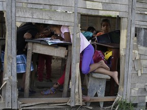 In this May 8, 2018 photo, children study at a run down school in the Amazonian shantytown of Victoria Gracia, Peru. In April Olivia Arevalo, a plant healer of the Shipibo-Konibo tribe, was allegedly shot to death by a Canadian man in Victoria Garcia.