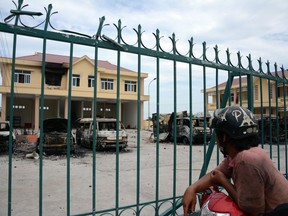 In this photo taken on Tuesday June 12, 2018, a motorist looks at charred vehicles burned by protesters at a fire and police station in the south central province of Binh Thuan, Vietnam. Vietnamese protesters clashed with police on Sunday and Monday in the province to protest over a proposed law on special economic zones they fear will be dominated by Chinese investors. The National Assembly on Monday voted to put on hold the legislation for several months. State media reported that police in the south central province of Binh Thuan on Sunday night used tear gas and water cannons but failed to prevent protesters from entering a government building they later vandalized. (AP Photo)