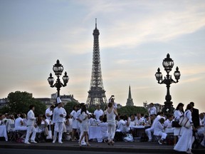 FILE - In this Thursday, June 12, 2014 file photo, participants dressed in white take part in Diner en Blanc, or White Dinner, at the Invalides gardens, in Paris. The 30th anniversary of the international dining event known as "Diner en Blanc," or "Dinner in White," is being held in the French capital on Sunday night June 3, 2018.