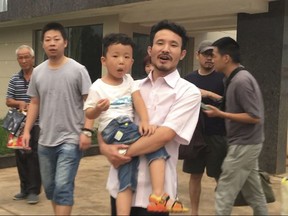 FILE - In this June 28, 2017 file image taken from video, Chinese labor activists Hua Haifeng, center, carries his son Bo Bo, and Li Zhao, second left, leave a police station after being released in Ganzhou in southern China's Jiangxi Province. China Labor Watch says three activists who were arrested while investigating abuses at Ivanka Trump's Chinese suppliers last year were released from bail on Tuesday June 26, 2018, but questions remain about their ability to live and work freely.