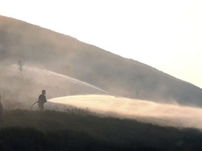 Firefighters damp-down the scorched land as they tackle a wildfire on Saddleworth Moor, England, which continues to spread and police have declared the blaze as a major incident, Wednesday June 27, 2018. The fire started on Sunday then reignited Monday amid Britain's heatwave and has devastated land around the village of Carrbrook, forcing the evacuation of nearby homes.