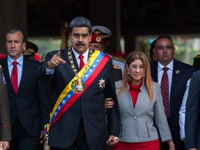 Nicolas Maduro, Venezuela's president, center, gestures as he walks with Cilia Flores, first lady of Venezuela, during a 'Vow of Loyalty' event at the Ministry of Defense in Caracas, Venezuela, on Thursday, May 24, 2018.