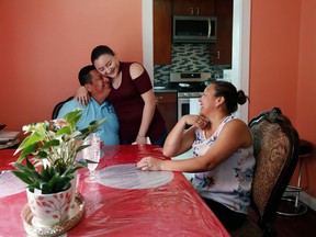In this May 25, 2018 photo, Nilson Canenguez, left, who is on the Temporary Protected Status program, or TPS, hugs his daughter Maybelin as his wife Judit looks on at their home in Morningside, Maryland. The father of three who came to the U.S. from El Salvador with virtually nothing is returning, after 20 years and as the owner of a construction business with dozens of employees, before his temporary legal residency is ended by the Trump administration.