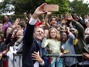 French President Emmanuel Macron takes a selfie with children during a WWII ceremony to mark the 78th anniversary of late French Gen. Charles de Gaulle's resistance call from London of June 18, 1940, at the Mont Valerien memorial in Suresnes, near Paris, France, Monday, June 18, 2018.