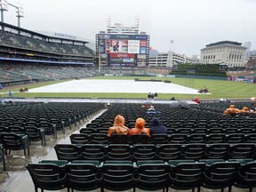 Fans wait in the rain for the start of the Detroit Tigers baseball game against the Cleveland Indians Saturday, June 9, 2018, in Detroit.