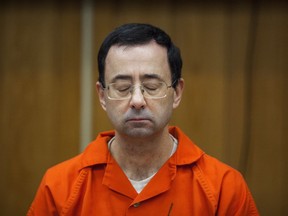 FILE - In this Feb. 5, 2018, file photo, Larry Nassar listens during his sentencing at Eaton County Circuit Court in Charlotte, Mich.  Michigan State University board trustee Brian Mosallam is asking interim school president John Engler to resign immediately.  Mosallam released a statement Friday, June 15, saying the crisis on campus related to Larry Nassar will not settle until Engler steps down.