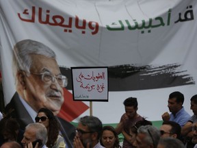 Palestinians attend a protest to demand lifting the sanctions on Gaza Strip, in the West Bank city of Ramallah, Tuesday, June 12, 2018. Placard reads: "Sanctions on Gaza are a crime, lift them" and on the banner showing President Mahmoud Abbas: "We love you and we pledge allegiance to you".