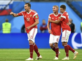 Russia's Artyom Dzyuba, left, celebrates after scoring his side's third goal with teammates Roman Zobnin and Yuri Gazinsky, from right, during the group A match between Russia and Egypt at the 2018 soccer World Cup in the St. Petersburg stadium in St. Petersburg, Russia, Tuesday, June 19, 2018.