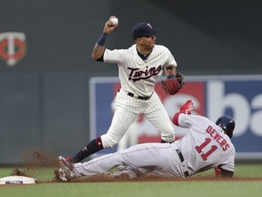Minnesota Twins shortstop Ehire Adrianza turns a double play getting Boston Red Sox Rafael Devers (11) out at second in the fourth inning of a baseball game Wednesday, June 20, 2018, in Minneapolis.