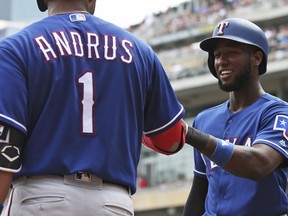 Texas Rangers' Jurickson Profar, right, smiles as Elvis Andrus congratulates him after Profar scored on a two-run single by Delino DeShields off Minnesota Twins pitcher Jake Odorizzi in the second inning of a baseball game Saturday, June 23, 2018, in Minneapolis.