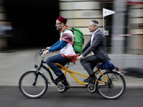 A Muslim and a Jewish man rides a tandem together during a bicycle tandem tour of Jews and Moslems against anti-Semitism and hatred of Muslims in Berlin, Sunday, June 24, 2018.