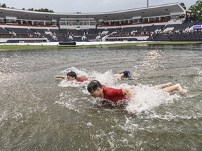 Jack Burkes, foreground, and Cole Catalano swim in the water in the outfield following heavy rainfall at Oxford-University Stadium before the start of the Missouri State-Tennessee Tech NCAA college baseball regional tournament game in Oxford, Miss., Friday, June 1, 2018.