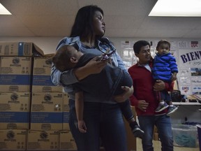 Immigrant parents hold their children at Catholic Charities of the Rio Grande Valley on Thursday, in McAllen, Texas. President Donald Trump ended family separations at the Mexican border but the U.S. government has done little to help with the reunifications, attorneys say.