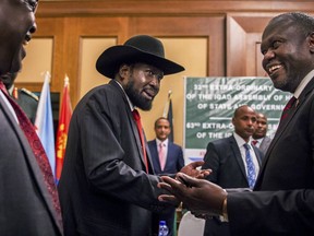 South Sudan's President Salva Kiir, center, and opposition leader Riek Machar, right, shake hands during peace talks at a hotel in Addis Ababa, Ethiopia, Thursday, June 21, 2018. South Sudan's armed opposition on Thursday rejected any "imposition" of a peace deal to end the five-year civil war and asked for more time after the first face-to-face meeting between President Salva Kiir and rival Riek Machar in almost two years.