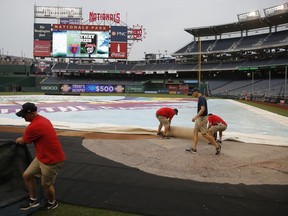 Members of the grounds crew adjust the tarp on the field before baseball game between the Washington Nationals and the Baltimore Orioles at Nationals Park, Wednesday, June 20, 2018, in Washington.