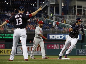 Washington Nationals' Juan Soto (22) is sent home to score by third base coach Bob Henley (13) as Philadelphia Phillies second baseman Jesmuel Valentin, center, looks on during the second inning of a baseball game at Nationals Park, Friday, June 22, 2018, in Washington.