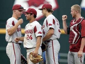 Arkansas' players from left: Jared Gates, Dominic Fletcher (24), Jake Reindl (34) and Grant Koch celebrate after an NCAA College World Series baseball game against Texas Tech in Omaha, Neb., Wednesday, June 20, 2018. Arkansas won 7-4.