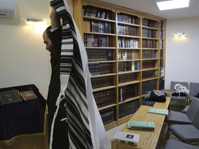 In this Wednesday, May 30, 2018, Rabbi Arie Zeev Raskin, the leader of Cyprus' 3,500-strong Jewish community, puts on a tallit, or prayer shawl, at a synagogue in Cyprus' Jewish Community Center in the town of Larnaca, as he prepares to handle two rare Torah scrolls that were stolen by the Nazis in WW2 and recovered by the Soviet Red Army. The scrolls will be put in an exhibition in a new museum on the eastern Mediterranean island-nation that its founders envision as a bridge-builder to the Arab world and beyond, a place where visitors who may never set foot in Israel can learn about the Jewish faith, the Holocaust and the tumultuous beginnings of the Jewish state.