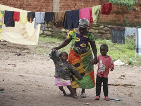 In this photo taken on Monday June 4, 2018, Marie Charline Mutsuva walks with children at a home she runs in Beni in eastern Congo. Hundreds of children have been orphaned by rebel attacks in remote Congo, and many end up in Marie Charline Mutsuva's care. The 65-year-old, once abandoned by her husband because she couldn't have children of her own, has taken in more than 100 youth over the past four years. Resources are so stretched that at times she sells her possessions, but she carries on: "I have family again."