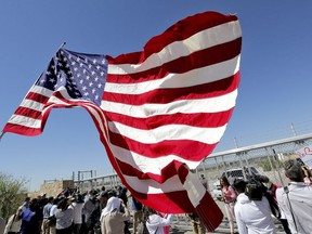 FILE - In this June 21, 2018 file photo, protesters and media gather outside a closed gate at the Port of Entry facility, where tent shelters are being used to house separated family members in Fabens, Texas.  The tumult of the past week along the southern border crystalized how the GOP has shifted from the "compassionate" conservatism George W. Bush articulated to win the presidency twice, buoyed by the support of 44 percent of Latinos in 2004. Instead, wrenching photos and audio of the U.S. government separating migrant children from their parents symbolize the tense relationship between Latinos and the White House in the Trump era.