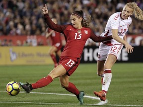 FILE - In this Jan. 21, 2018, file photo, United States forward Alex Morgan, left, shoots on goal as Denmark forward Stine Larsen, right, defends during the second half of an international friendly soccer match in San Diego. She's already an internationally recognized soccer player with a World Cup title and an Olympic gold medal. She's also the author of a series of kids' books. Now you can add actor to Alex Morgan's resume. The U.S. national team forward makes her theatrical debut in a new feature "Alex & Me" about a young player who is inspired by Morgan.