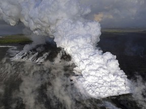 FILE - This Wednesday, June 6, 2018 photo provided by the U.S. Geological Survey shows a laze (lava haze) plume rising from the northern side of the fissure 8 lava flow margins in the former Kapoho Bay at the town of Kapoho on the island of Hawaii. On Tuesday, June 19, 2018, The Associated Press has found that stories circulating on the internet that the ongoing eruption of the Kilauea volcano in Hawaii is causing crystals to rain from the sky are untrue. (U.S. Geological Survey via AP)