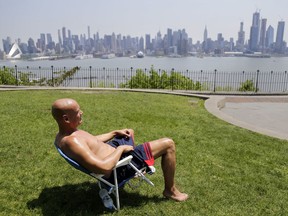 FILE - In this Tuesday, May 15, 2018 file photo, Rick Stewart sits in the sunshine with the New York City skyline in the background, in a park in Weehawken, N.J. According to weather records released on Wednesday, June 6, 2018, May reached a record 65.4 degrees in the continental United States, which is 5.2 degrees above the 20th century average.