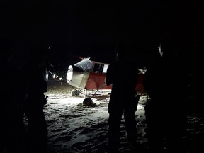 In this June 24, 2018 photo, Coast Guard personnel stand in front of a plane on a secured beach on the southeast side of Training Center Cape May in Cape May, N.J., after it landed illegally and there was no sign of the pilot. The Coast Guard says officers became aware of the incident when the plane was spotted on closed-circuit cameras.