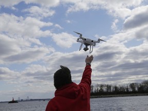FILE- In this April 29, 2018, file photo, a drone operator helps to retrieve a drone after photographing over Hart Island in New York. Science advisers to the federal government say safety regulators should do more to speed the integration of commercial drones into the nation's airspace. The National Academies of Science, Engineering and Medicine said in a report Monday that federal safety regulators are often "overly conservative" and need to balance the overall benefits of drones instead of focusing only on their risk to airplanes and helicopters.
