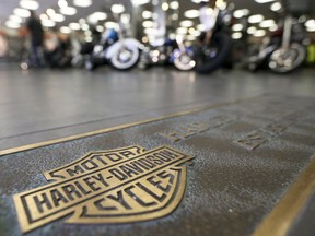 FILE- In this April 26, 2017, file photo, rows of motorcycles are behind a bronze plate with corporate information on the showroom floor at a Harley-Davidson dealership in Glenshaw, Pa. The European Union will start taxing on Friday a range of imports from the U.S., including quintessentially American goods like Harley-Davidson bikes and cranberries, in response to President Donald Trump's decision to slap tariffs on European steel and aluminum.