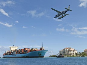 FILE- In this May 5, 2018, file photo, a Tropic Ocean Airways seaplane flies over the container ship Gerd Maersk as the ship heads to Port Miami in Miami Beach, Fla. On Wednesday, June 6, the Labor Department issues revised data on productivity in the first quarter.