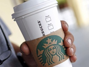 FILE- In this Aug. 10, 2017, file photo, a person holds a beverage from a Starbucks in Miami Springs, Fla. Starbucks says it's raising the price of a regular drip coffee by 10 cents to 20 cents this week in most U.S. stores. It says a small brewed coffee is now $1.95 to $2.15 in a majority of locations. The company said Thursday, June 7, 2018, that prices remain unchanged on drinks such as lattes and iced coffees in most stores.
