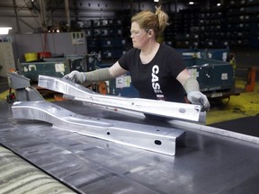 FILE- In this April 30, 2015, file photo, United Auto Workers line worker Crystal McIntyre unloads parts from a stamping machine at the General Motors Pontiac Metal Center in Pontiac, Mich. If President Donald Trump delivers on threats to slap 25 percent tariffs on imported automobiles and parts, experts say it will cut auto sales and cost jobs in the U.S., Canada and Mexico.
