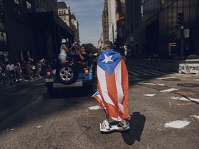 FILE - In this June 11, 2017 file photo, a man rolls on a hover-board along Fifth Avenue during the National Puerto Rican Day Parade in New York.  Amid all the fun and celebration planned for this years parade on Sunday, June 10, 2018, organizers and participants want to keep a spotlight on something serious. They want people to remember that months after Hurricane Maria roared through and as the next hurricane season arrives, Puerto Rico is still struggling.
