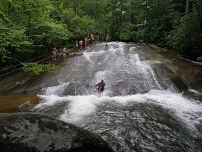 This May 18, 2018 photo shows two people riding down Sliding Rock, a natural waterslide located in the Pisgah National Forest, between Brevard, N.C., and the Blue Ridge Parkway. Known as "The Land of the Waterfalls," Transylvania County boasts more than 250 waterfalls that attract visitors every year.