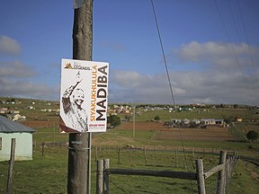 FILE - In this Dec. 7, 2013, file photo, a poster of Nelson Mandela is seen in front of the house of the former South African president in Qunu, South Africa. The centennial of Mandela's birth is July 18, and those wishing to make a pilgrimage to honor his legacy will find a number of sites around South Africa, from the villages of his childhood to museums and historic sites about apartheid.