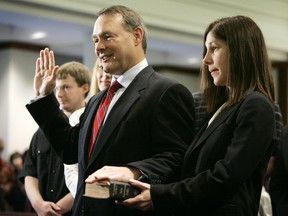 In this Jan. 2, 2007 file photo Iowa State Treasurer Michael Fitzgerald takes the oath of office as his fiance Susan Lowery, right, holds his Bible during a swearing-in ceremony for statewide elected officials in Des Moines, Iowa. Iowa politicians are scrambling to comply with a new and unusual state law that bans them from using taxpayer dollars if there's a whiff of self-promotion. The Iowa Ethics and Campaign Disclosure Board plans to release at least one advisory opinion next month on the law, which goes into effect Sunday, July 1, 2018. The provision prohibits statewide officials and lawmakers from tapping taxpayer dollars to promote their written name, likeness or voice through various platforms like television and radio.