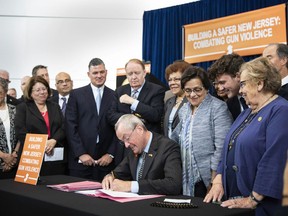 In this photo provided by the New Jersey Governor's Office, Gov. Phil Murphy, center, signs several gun safety bills at the Richard J. Hughes Justice Complex Atrium in Trenton, N.J., Wednesday, June 13 , 2018. The half-dozen new gun control laws tighten the state's already strict statutes.