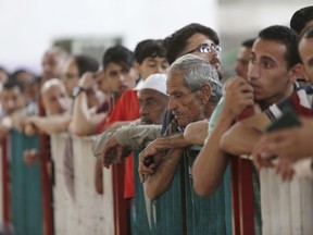 File-This May 22, 2018, file photo shows Palestinian passengers waiting to cross the border to the Egyptian side of Rafah crossing with Egypt, in Khan Younis, in the Gaza Strip. The United Nations is imploring member countries to fill a critical funding gap the Trump administration created by cutting $300 million that helped struggling Palestinian refugees across the Middle East. On Monday, June 25, 2018, the U.N. is holding a pledging conference to raise money for the most basic needs of 5 million refugees in the Gaza Strip, the West Bank, Jordan, Lebanon and Syria.
