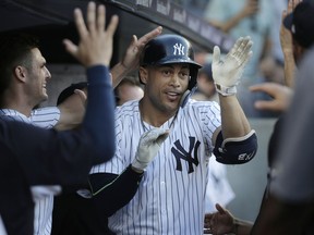 New York Yankees' Giancarlo Stanton is greeted by teammates after hitting a solo home run during the first inning of a baseball game against the Seattle Mariners at Yankee Stadium Tuesday, June 19, 2018, in New York.