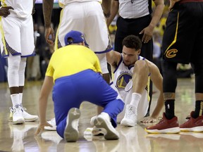Golden State Warriors guard Klay Thompson is helped off the floor during the first half of Game 1 of basketball's NBA Finals between the Warriors and the Cleveland Cavaliers in Oakland, Calif., Thursday, May 31, 2018.