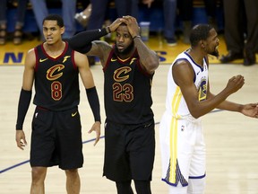 Cleveland Cavaliers forward LeBron James (23) reacts between guard Jordan Clarkson (8) and Golden State Warriors forward Kevin Durant during the second half of Game 1 of basketball's NBA Finals in Oakland, Calif., Thursday, May 31, 2018.