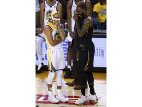 Golden State Warriors guard Stephen Curry, left, talks with Cleveland Cavaliers forward LeBron James during overtime of Game 1 of basketball's NBA Finals in Oakland, Calif., Thursday, May 31, 2018. The Warriors won 124-114.